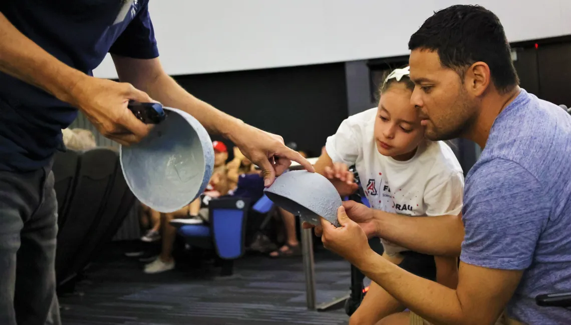 Father and daughter learn about the Moon with a 3d model of the lunar surface at a lecture at Flandrau planetarium in tucson